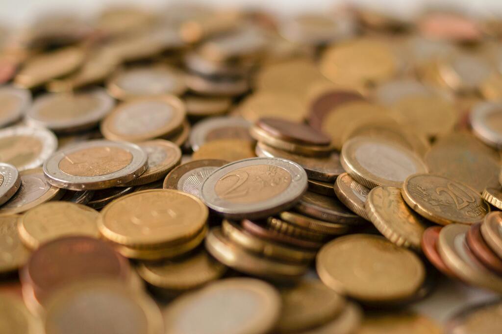 A variety of Euro coins scattered on a flat surface, showcasing different denominations in a warm light.